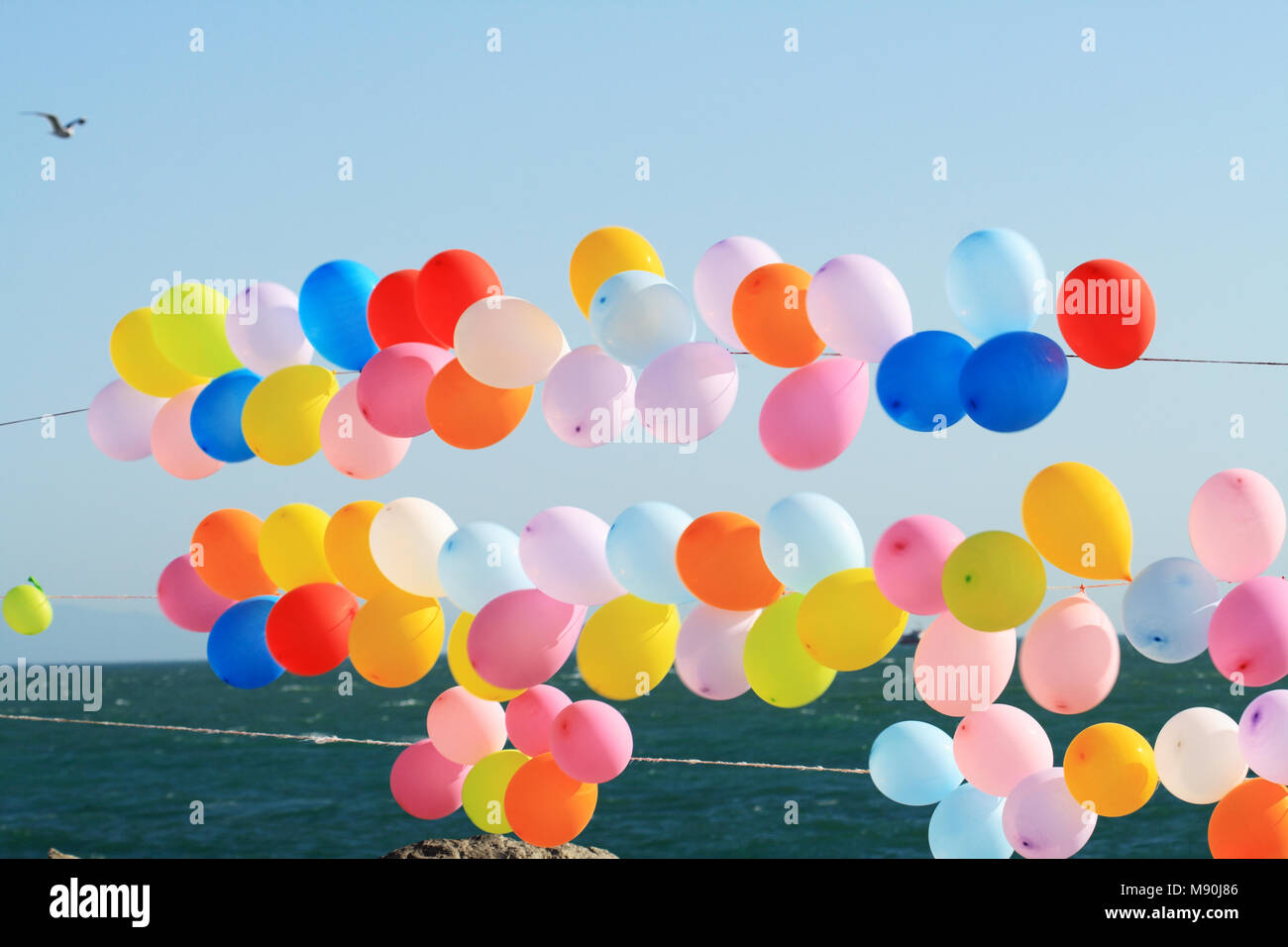 Lots of colorful balloons on background with blue sky and sea Stock Photo