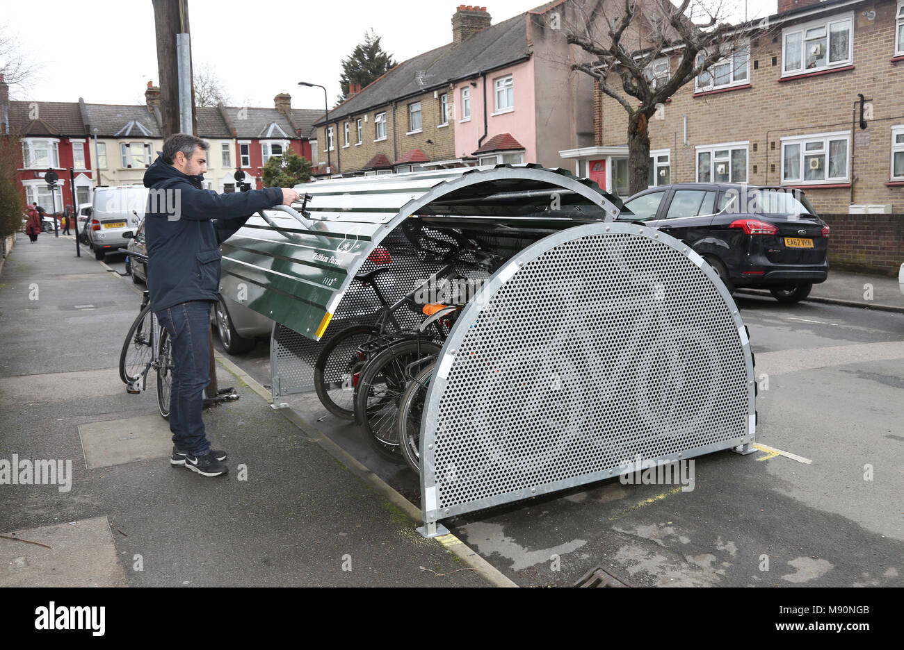 A cyclist places his bike into a secure on-street bicycle store recently installed on a residential London street. Stock Photo