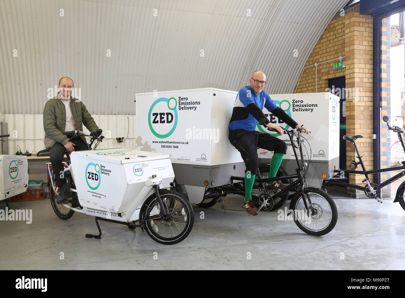 Staff from a Zero Emissions delivery company sit on electric cargo bikes used to distribute goods in Walthamstow, North London. Stock Photo