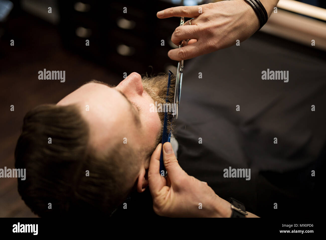Portrait from above of customer having beard trimmed by barber Stock