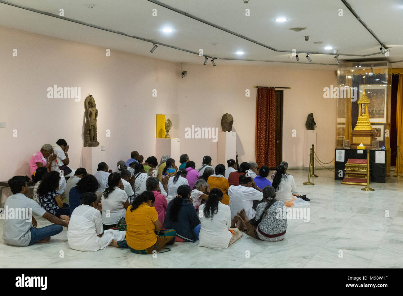 National museum of India, Delhi. Sri Lankan buddhist visitors praying near a reliquary. India. Stock Photo
