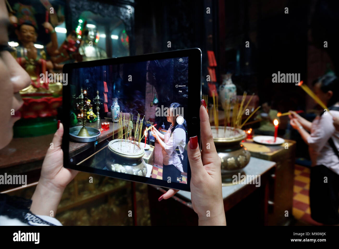 Woman using Ipad tablet to take a photograph.  Taoist temple. Emperor Jade pagoda (Chua Phuoc Hai).  Woman using Ipad tablet to take  photographs of c Stock Photo