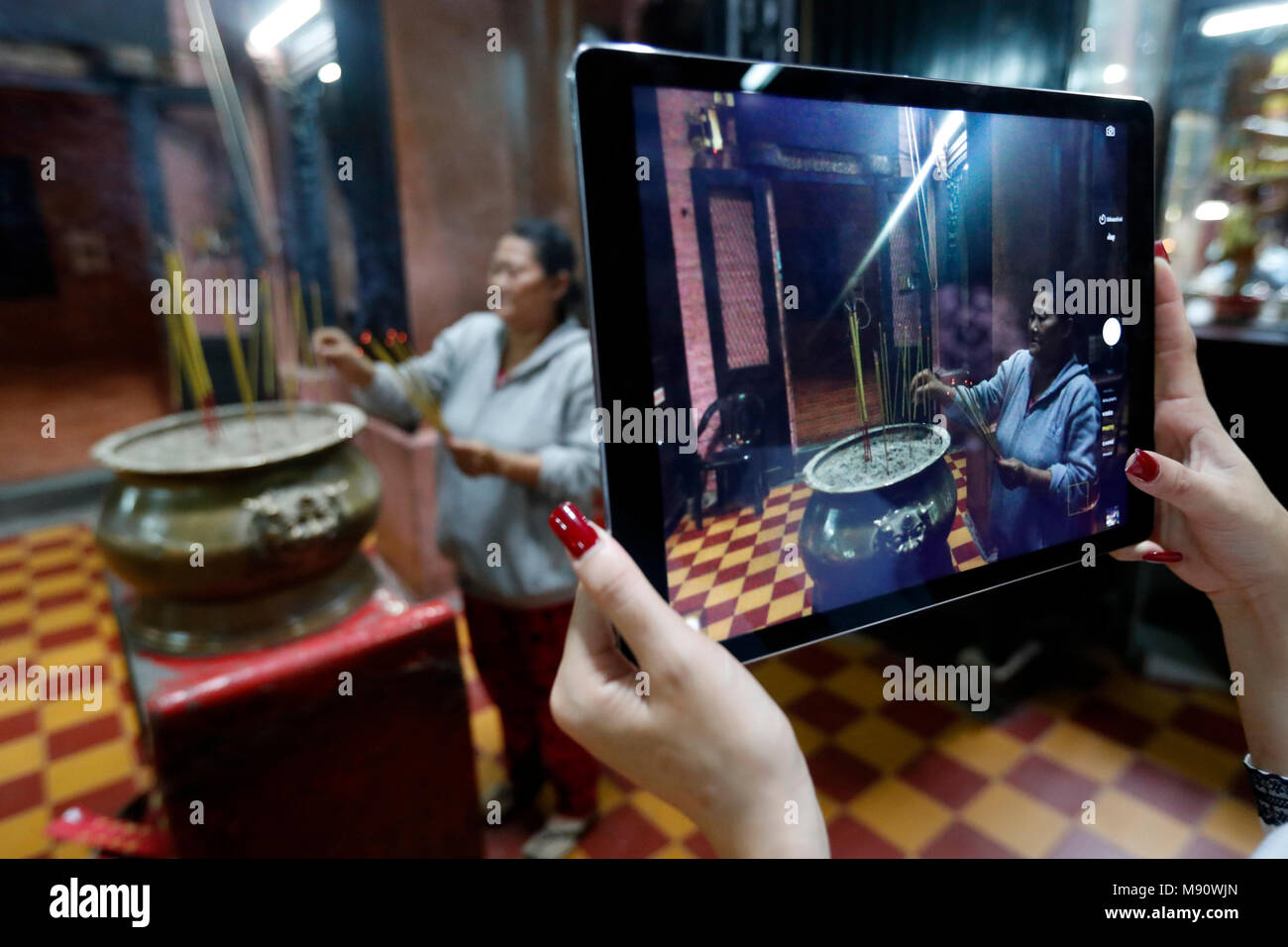 Woman using Ipad tablet to take a photograph.  Taoist temple. Emperor Jade pagoda (Chua Phuoc Hai).  Woman using Ipad tablet to take  photographs of c Stock Photo