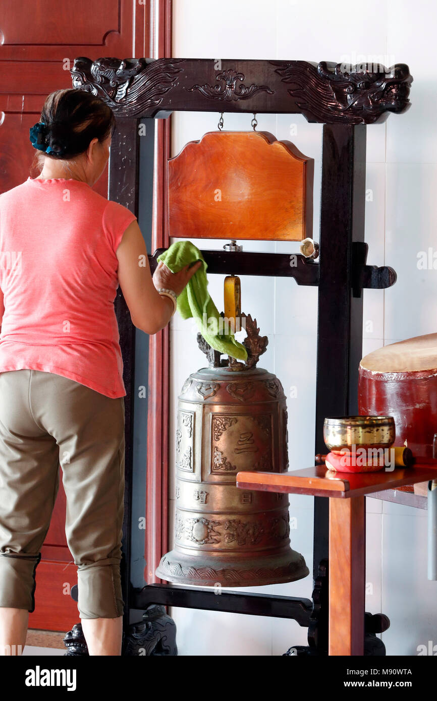 Chua Tu Quang buddhist temple. Woman cleaning bronze buddhist bell