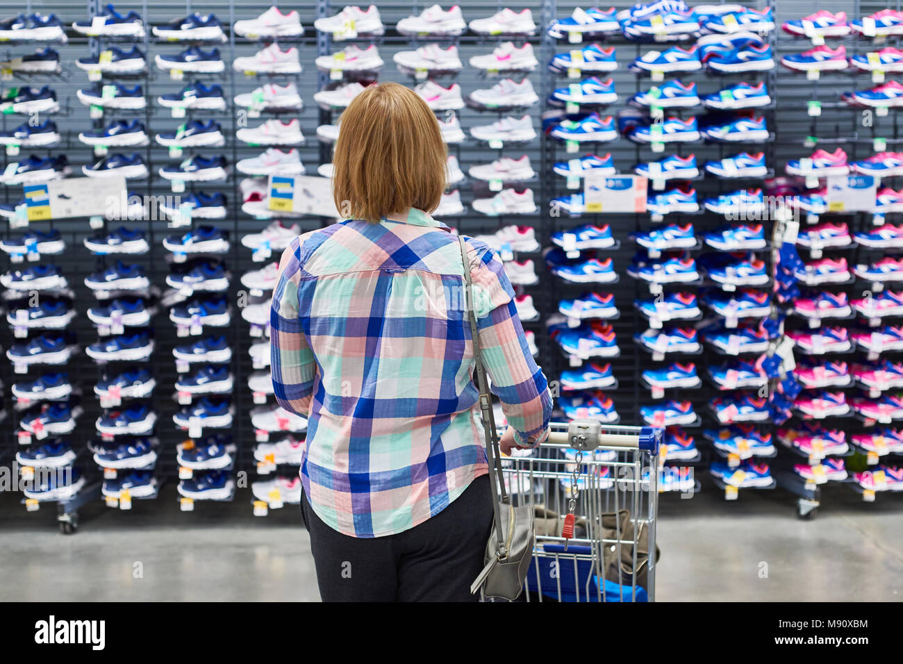 Woman chooses sneakers in a sports clothing store Stock Photo Alamy