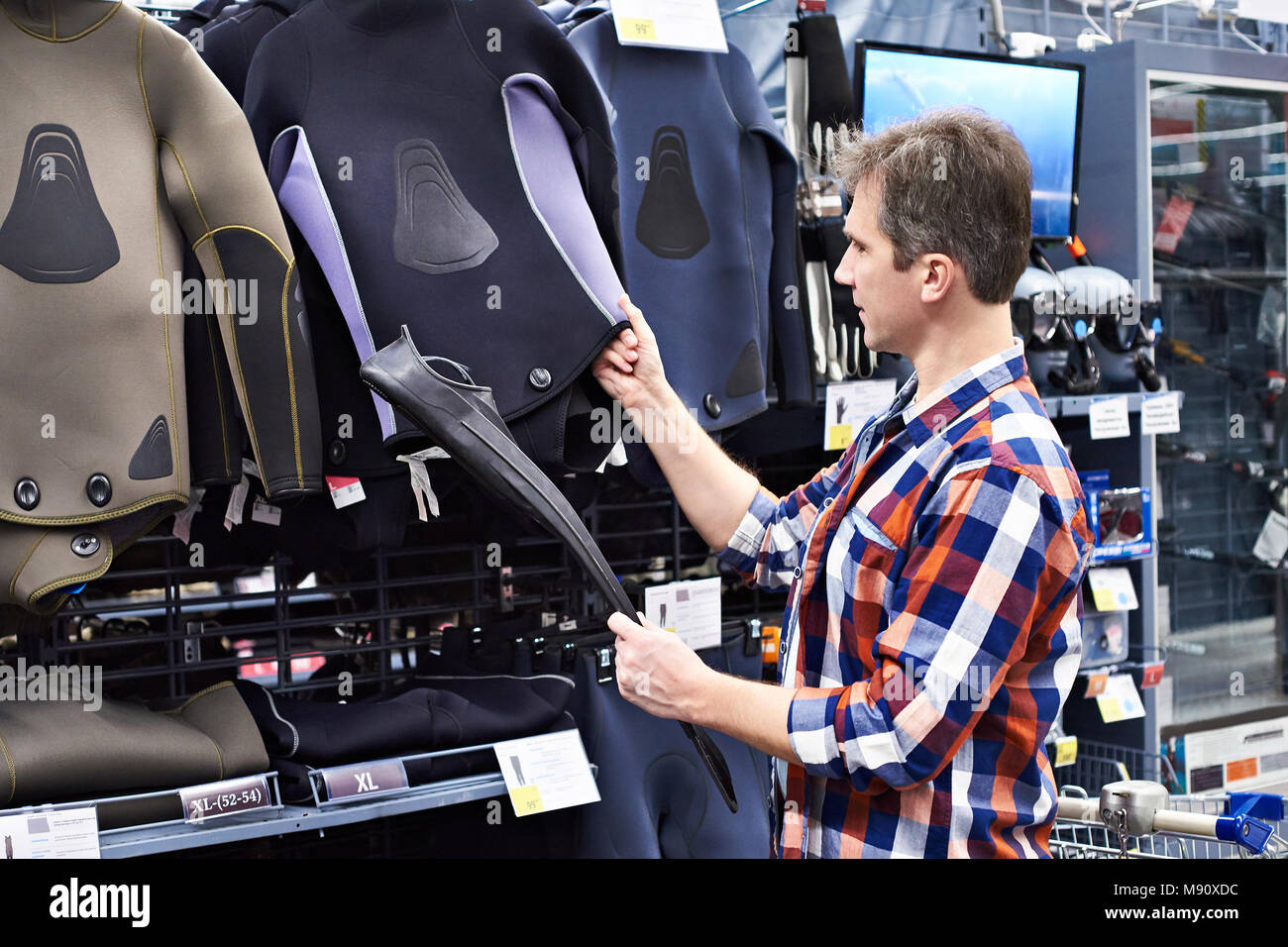 Man chooses a wetsuit and fins for spearfishing in a sports shop Stock Photo