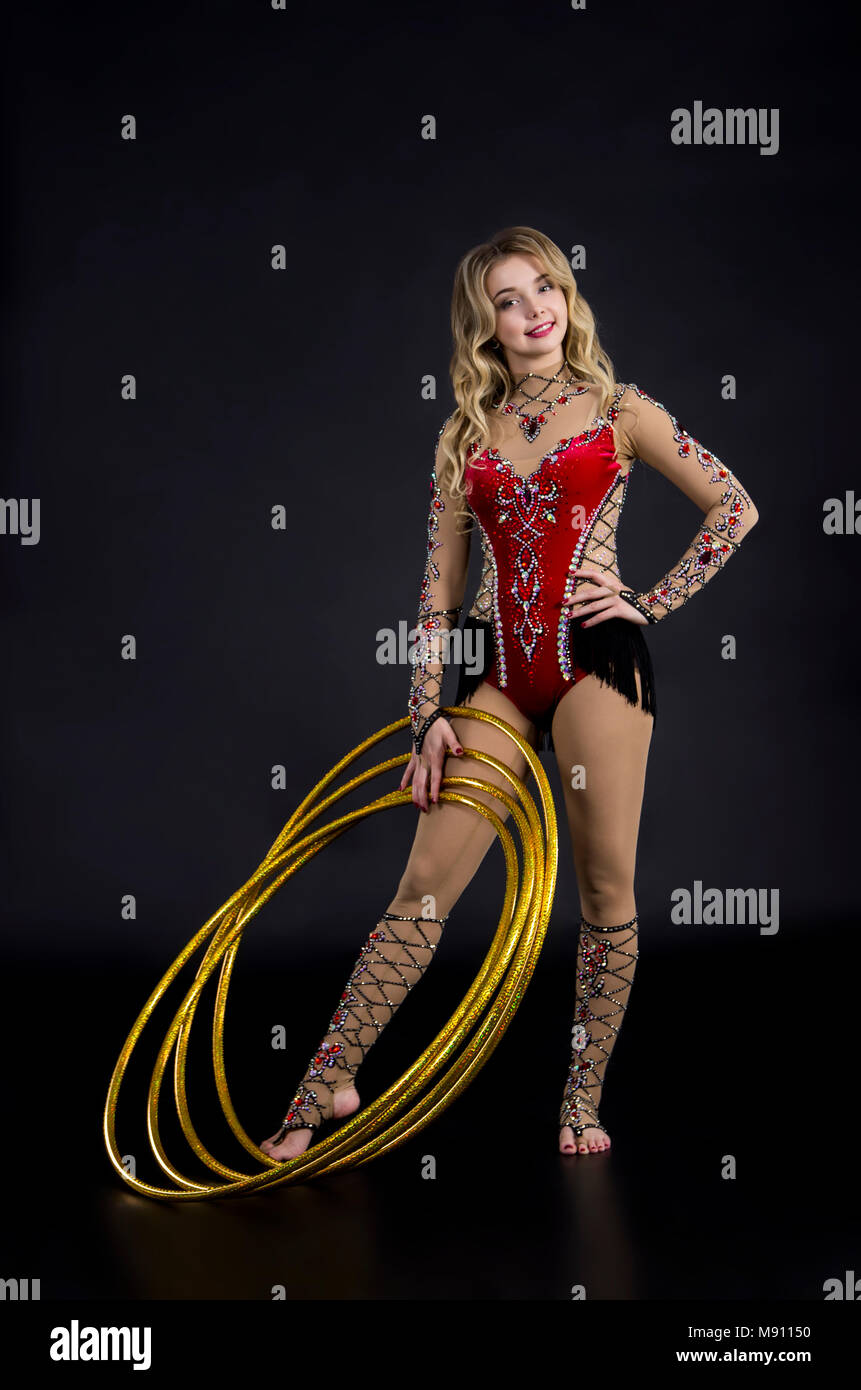 The contortionist woman in stage costume with hoops. Studio shot on dark background. Stock Photo
