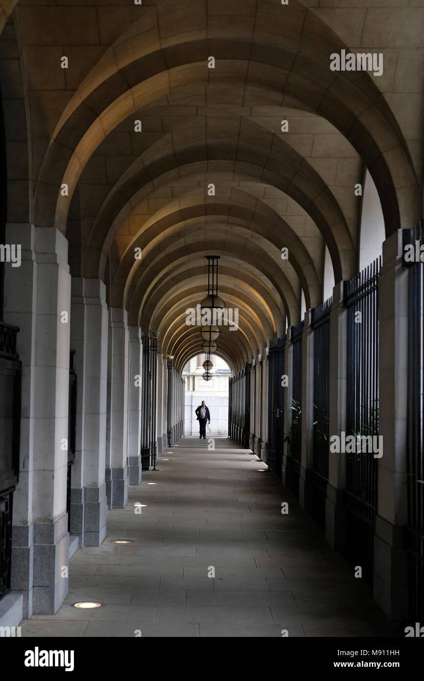 A man walking under the arches at Savoy Place, London. Stock Photo