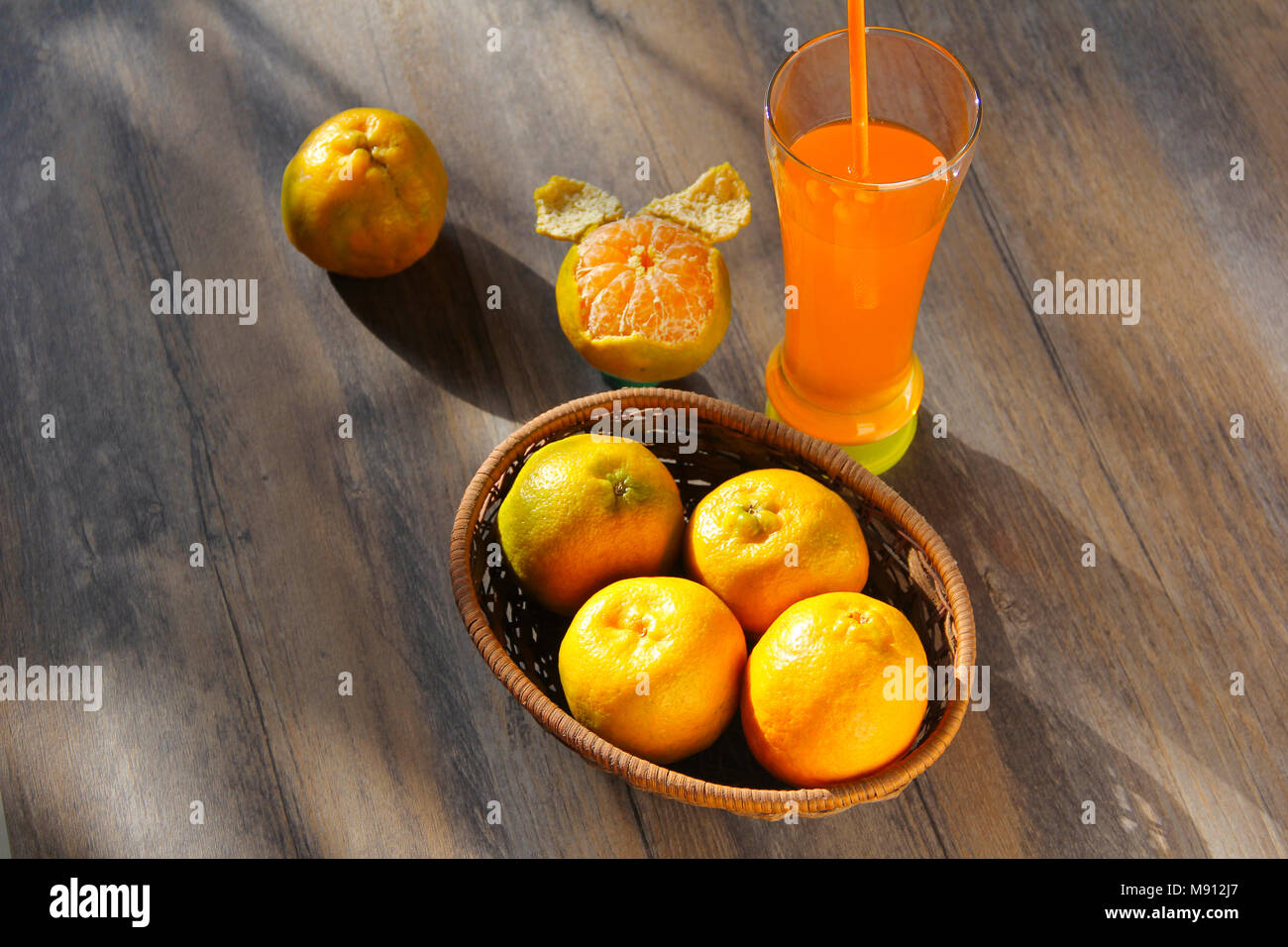 Fresh orange fruits with glass of orange juice isolated on wooden background Stock Photo