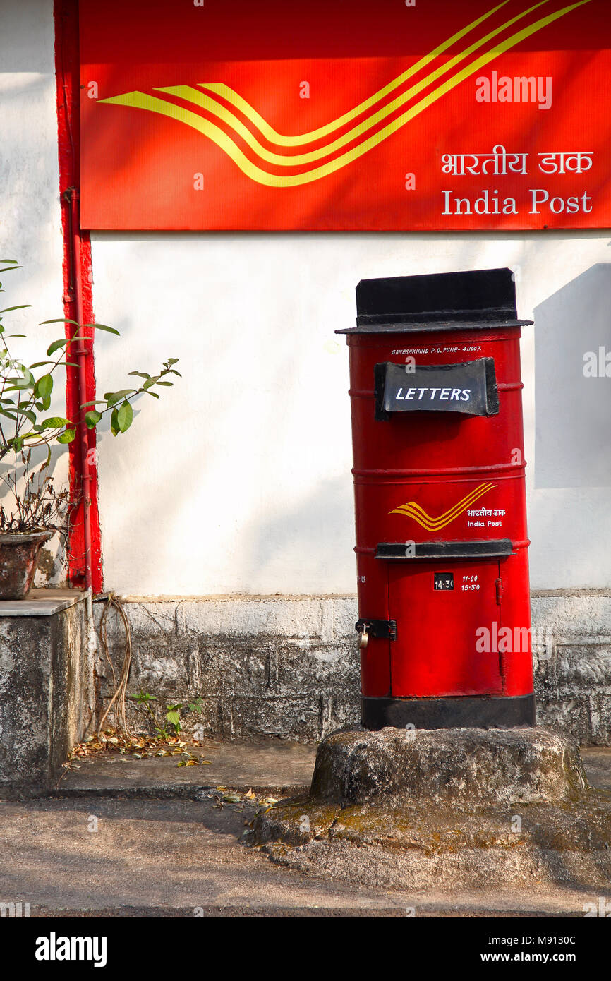 Red letter box with background of India Post, Pune University campus at Pune Stock Photo