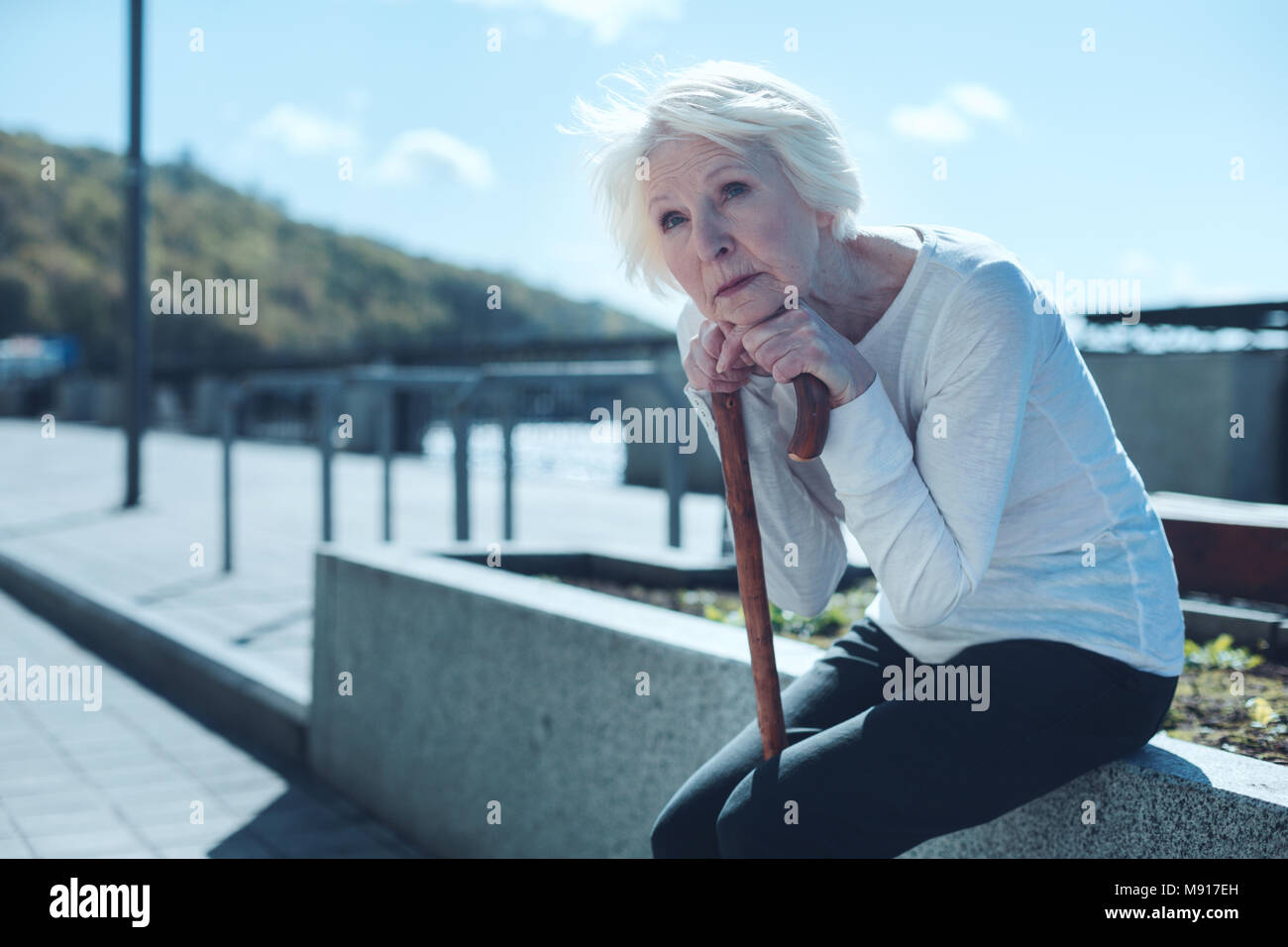 Nostalgic retired lady leaning on cane and dreaming Stock Photo