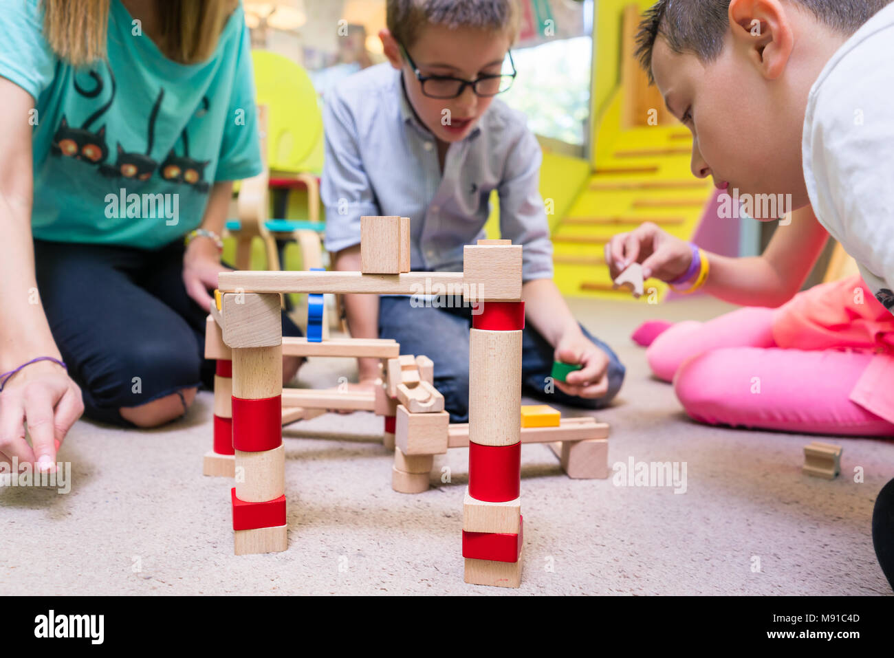 Female educator teaching children to build a train circuit Stock Photo