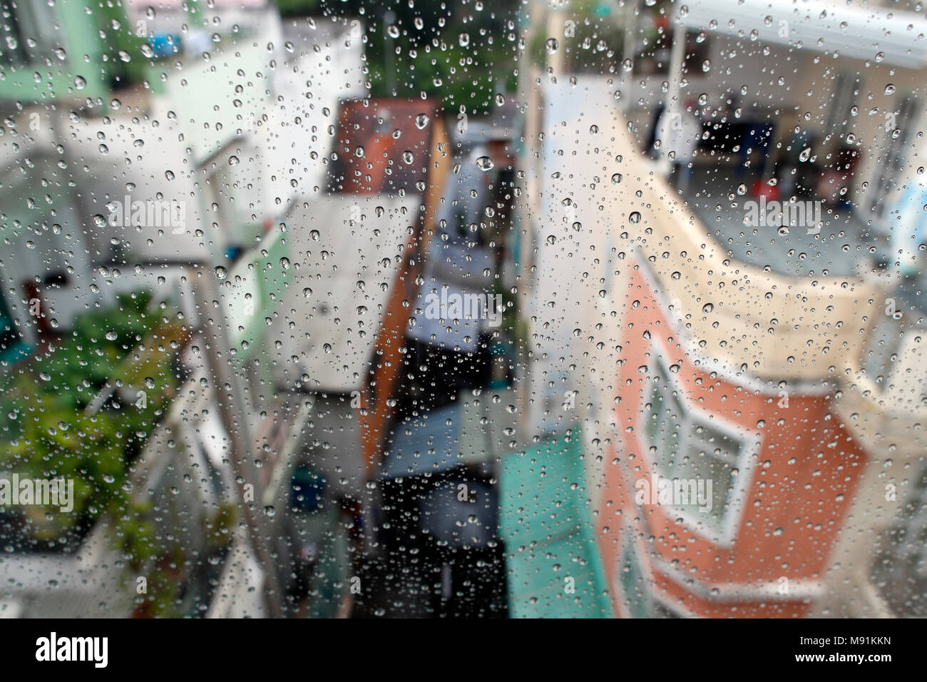 Monsoon season.  close-up of raindrops on glass window.  Drops of rain water on window, street scene in background.  Ho Chi Minh City. Vietnam. Stock Photo