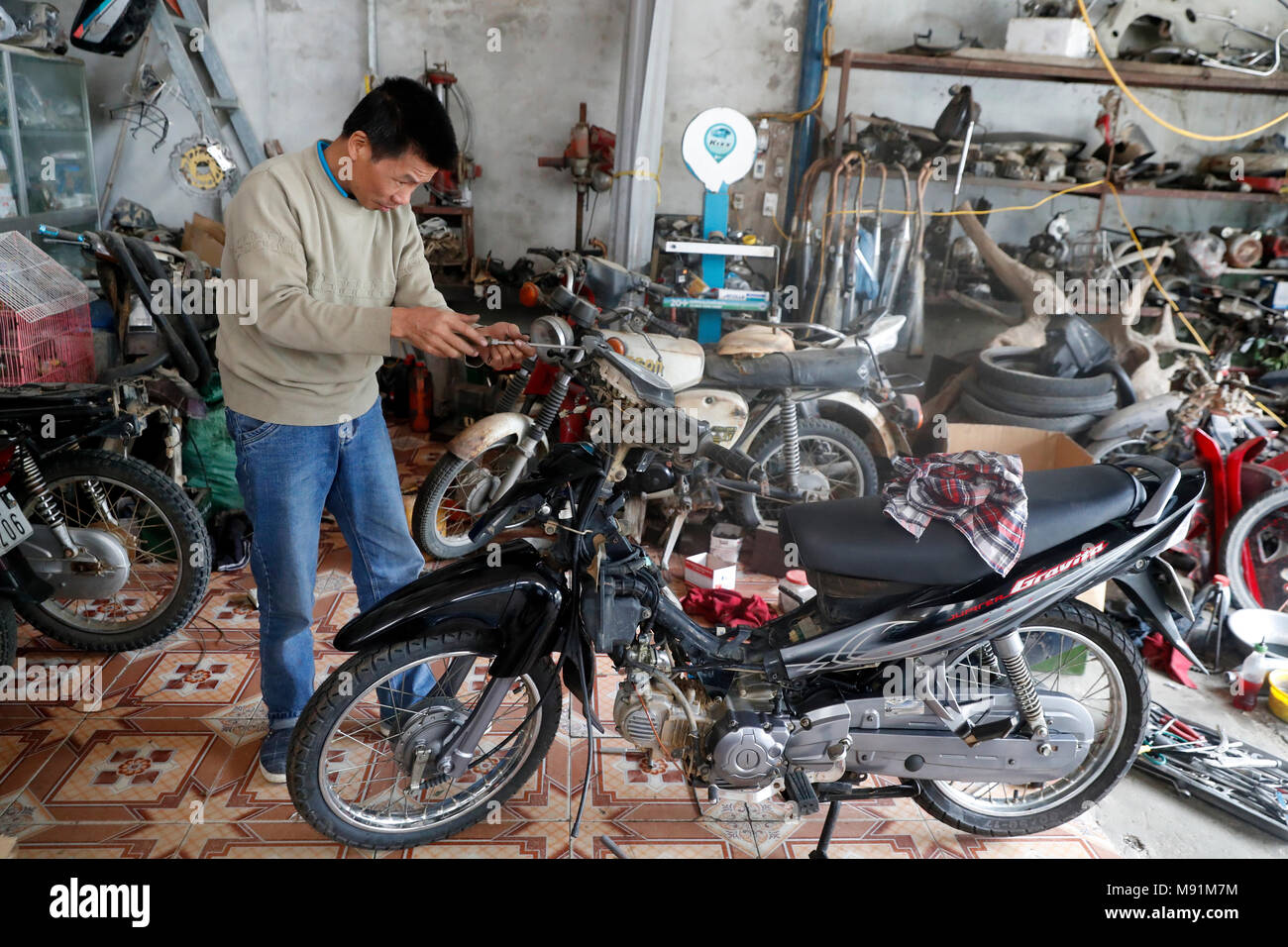 Man repairing his motorcycle in garage. Bac Son. Vietnam. Stock Photo