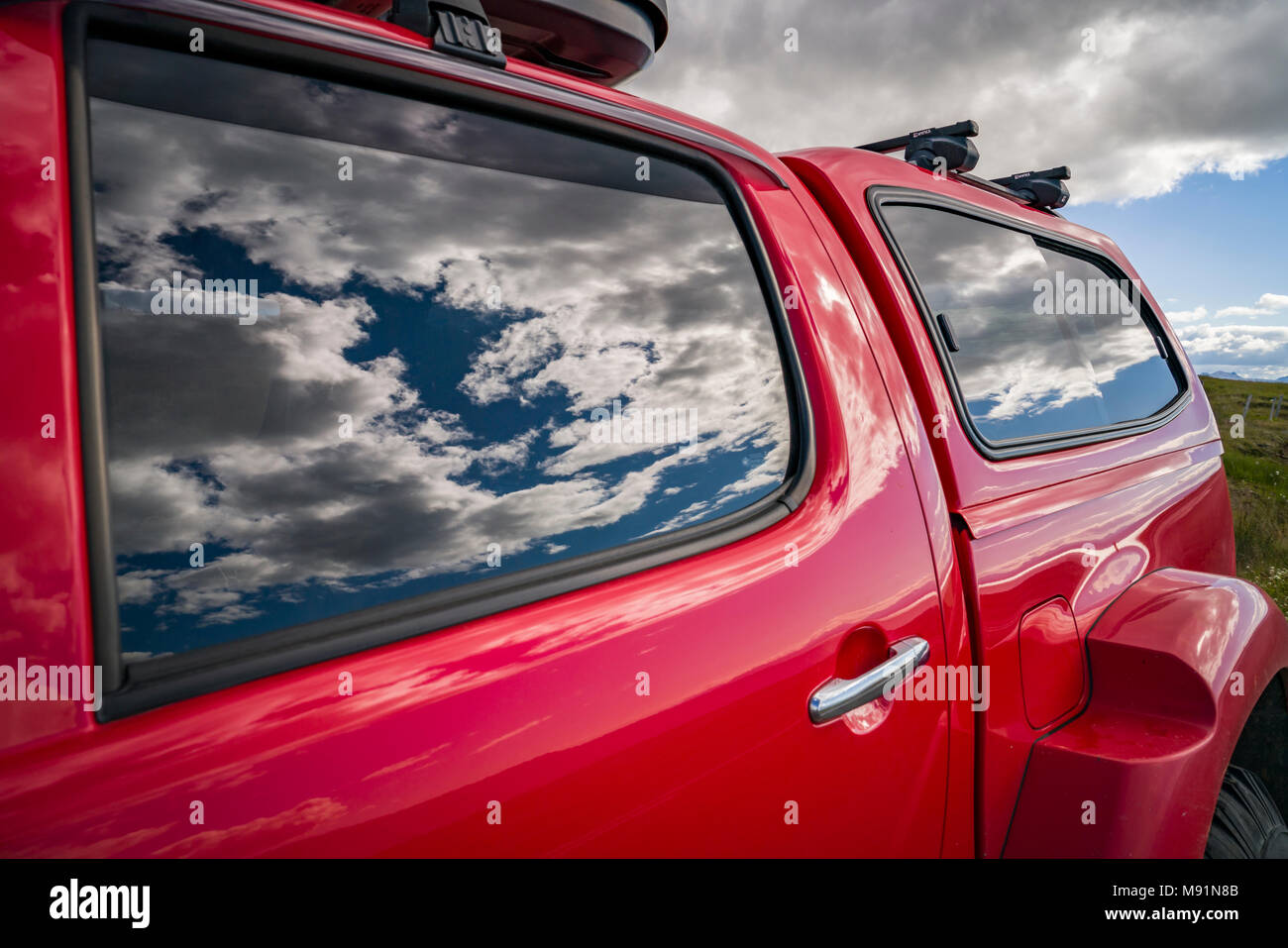 Side View of Red Truck with clouds reflecting in the windows. Stock Photo