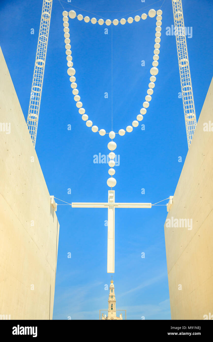 Giant rosary in the blue sky and bell tower of Basilica of Our Lady of Fatima on background. Fatima in Portugal is the site where three Portuguese Shepherd children saw the Virgin Mary of Rosary. Stock Photo