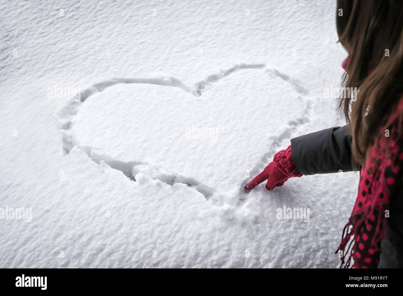 Woman drawing heart shape in the snow Stock Photo - Alamy