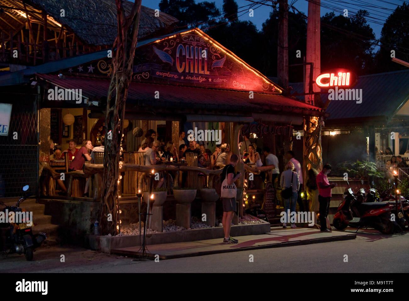The main street in Ella evening night time showing a typical restaurant, bar filled with tourists.  Slow shutter speed and high iso so motion blur. Stock Photo