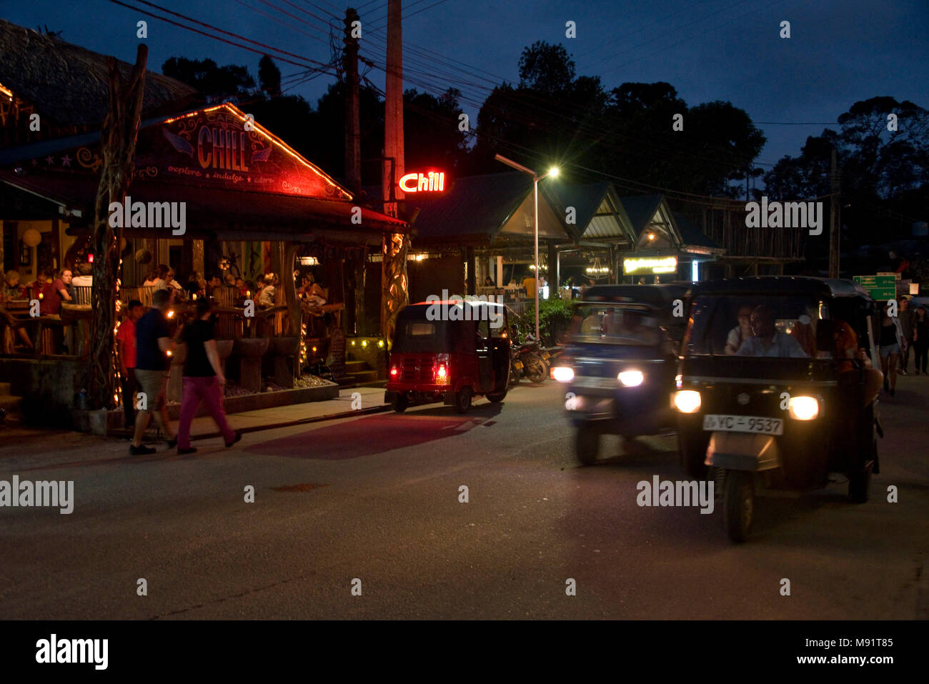 The main street in Ella evening night time with tuk tuks, restaurants, bars, tourists and locals.  Slow shutter speed and high iso so motion blur. Stock Photo