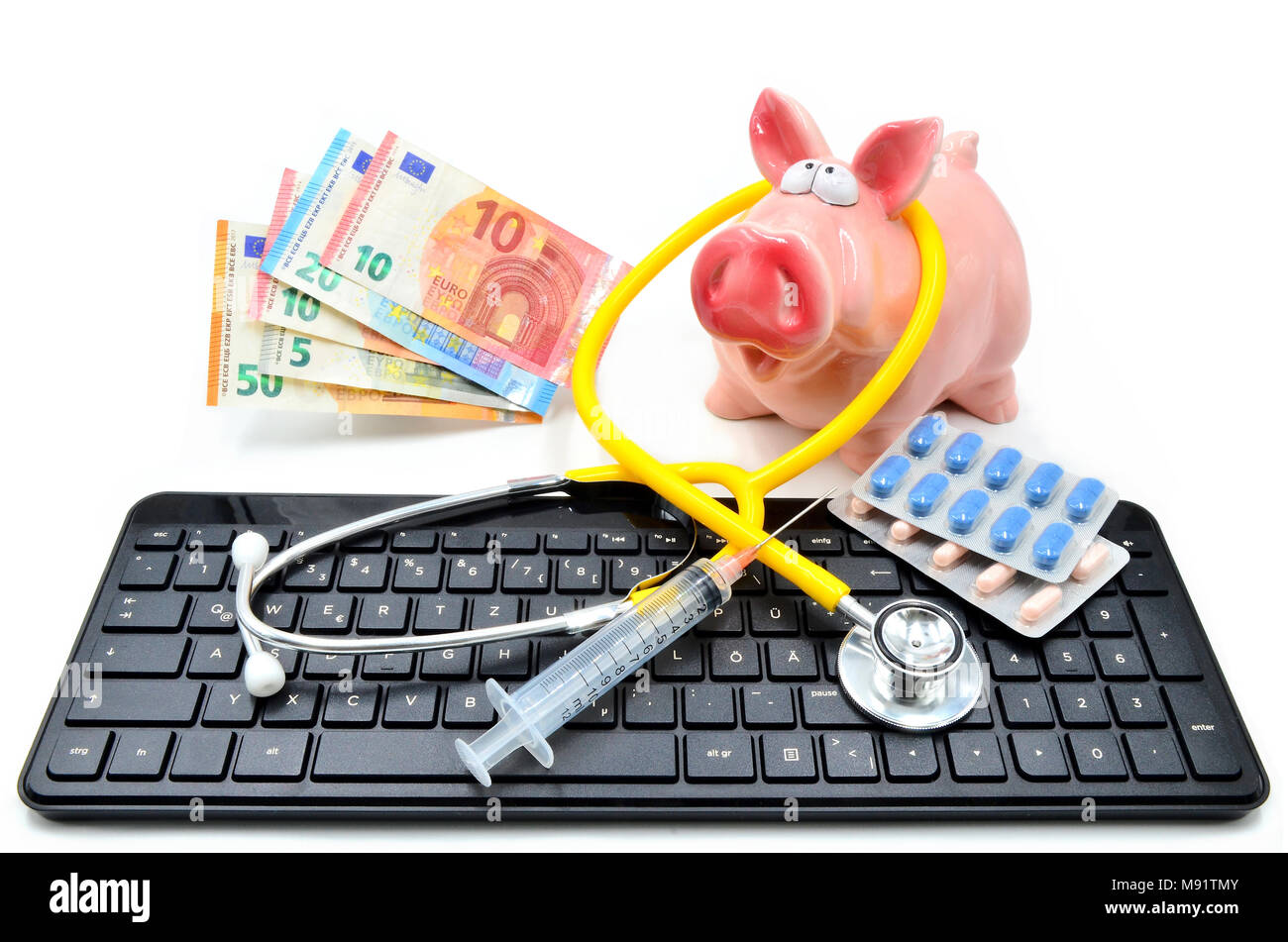 Desktop with piggybank euronotes and stethoscope, syringe, pills isolated Stock Photo
