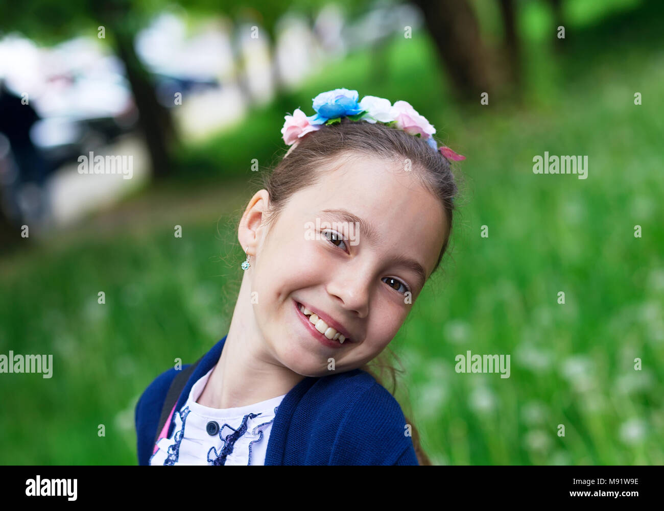 Cute Happy Girl Outdoors enjoying nature. Beautiful Teenage girl with long hair smiling at sunny day. Stock Photo