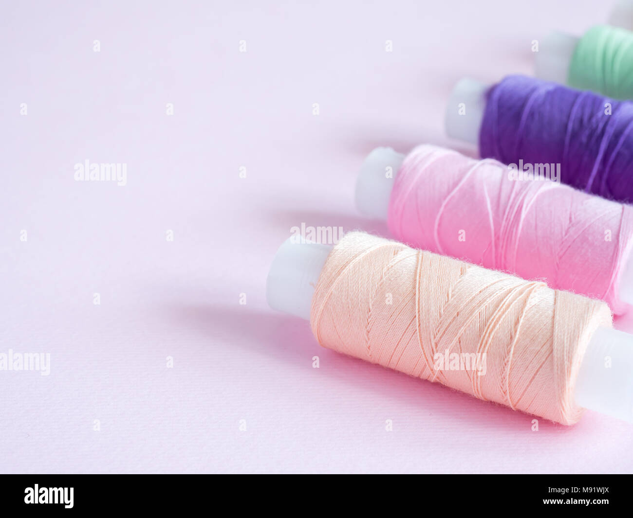 Colorful sewing buttons and thread on a pink background Stock Photo - Alamy