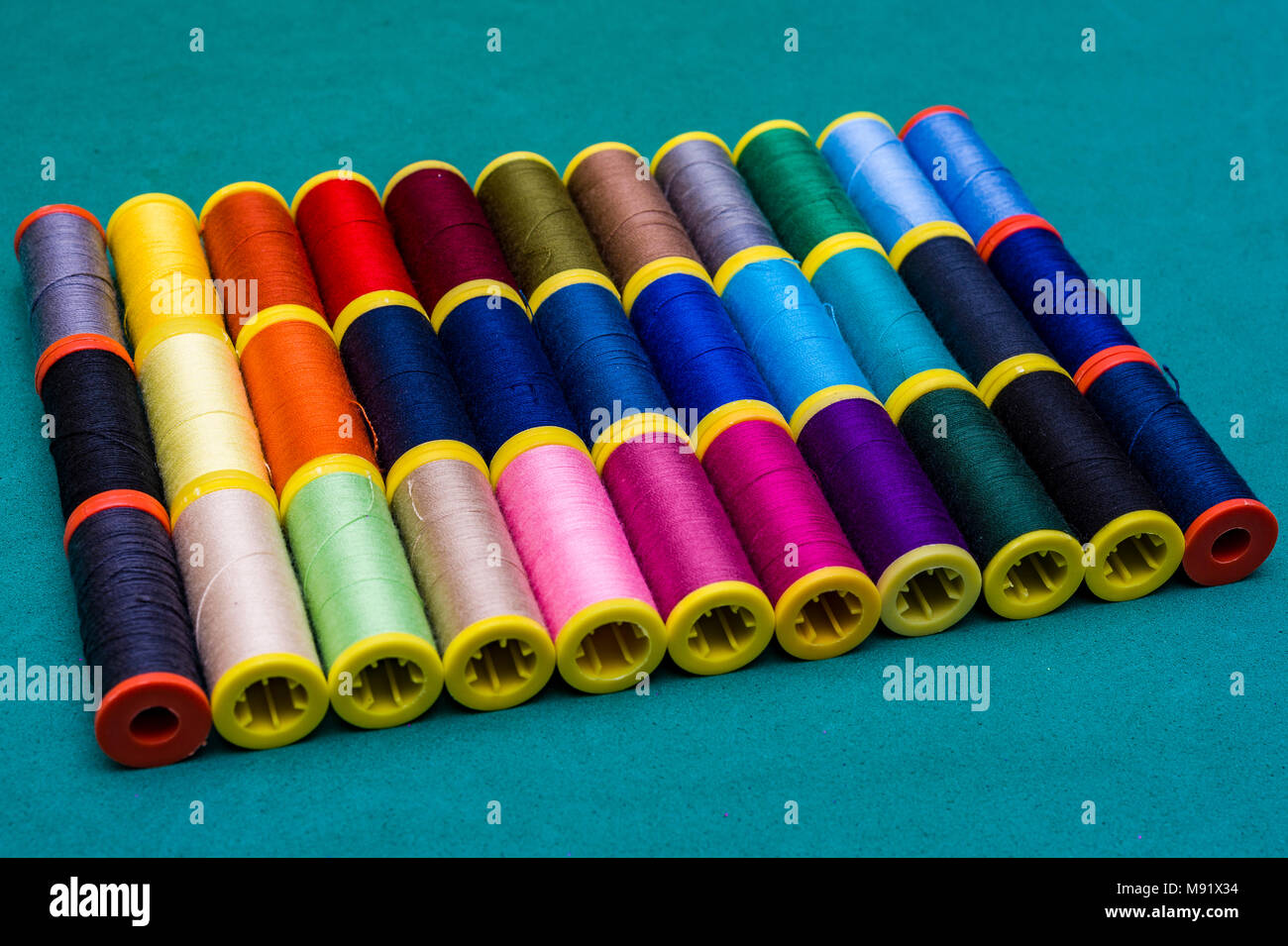 Multicolor sewing threads on background Colored threads in reels. Stock Photo