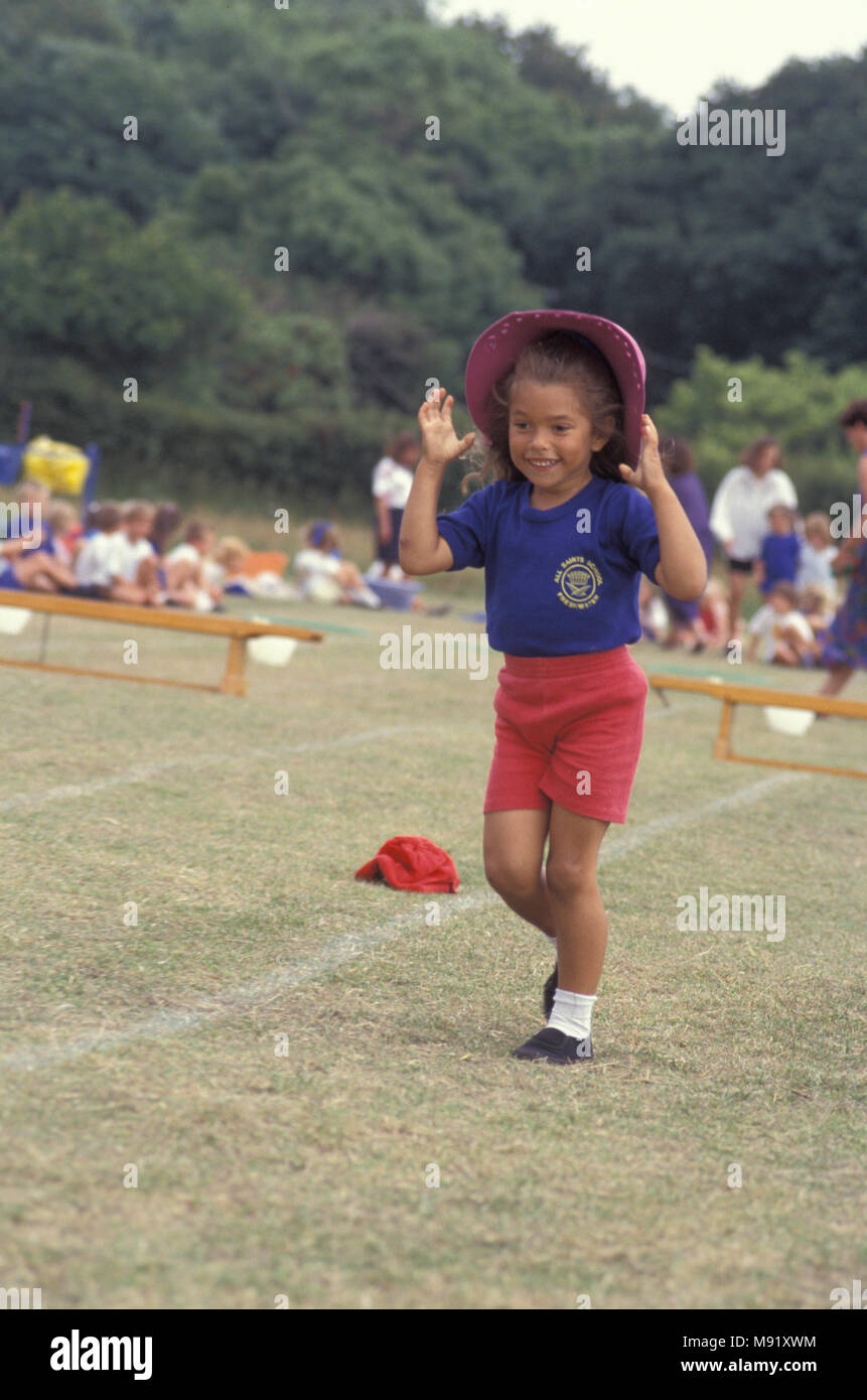 little girl competing in sports day game trying to keep hat on, England