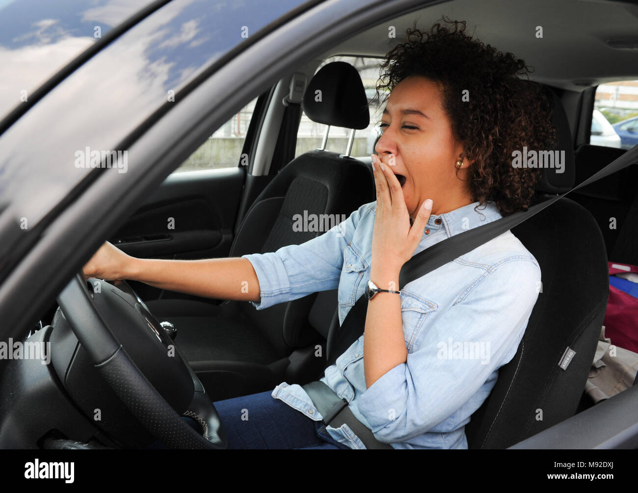 Portrait sleepy tired fatigued exhausted young attractive woman driving her car Stock Photo