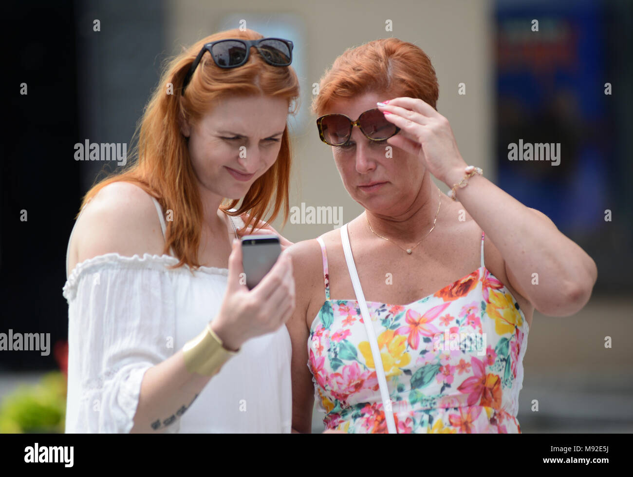 Mother and daughter looking at her cellphone in the street, Vilnius, Lithuania Stock Photo