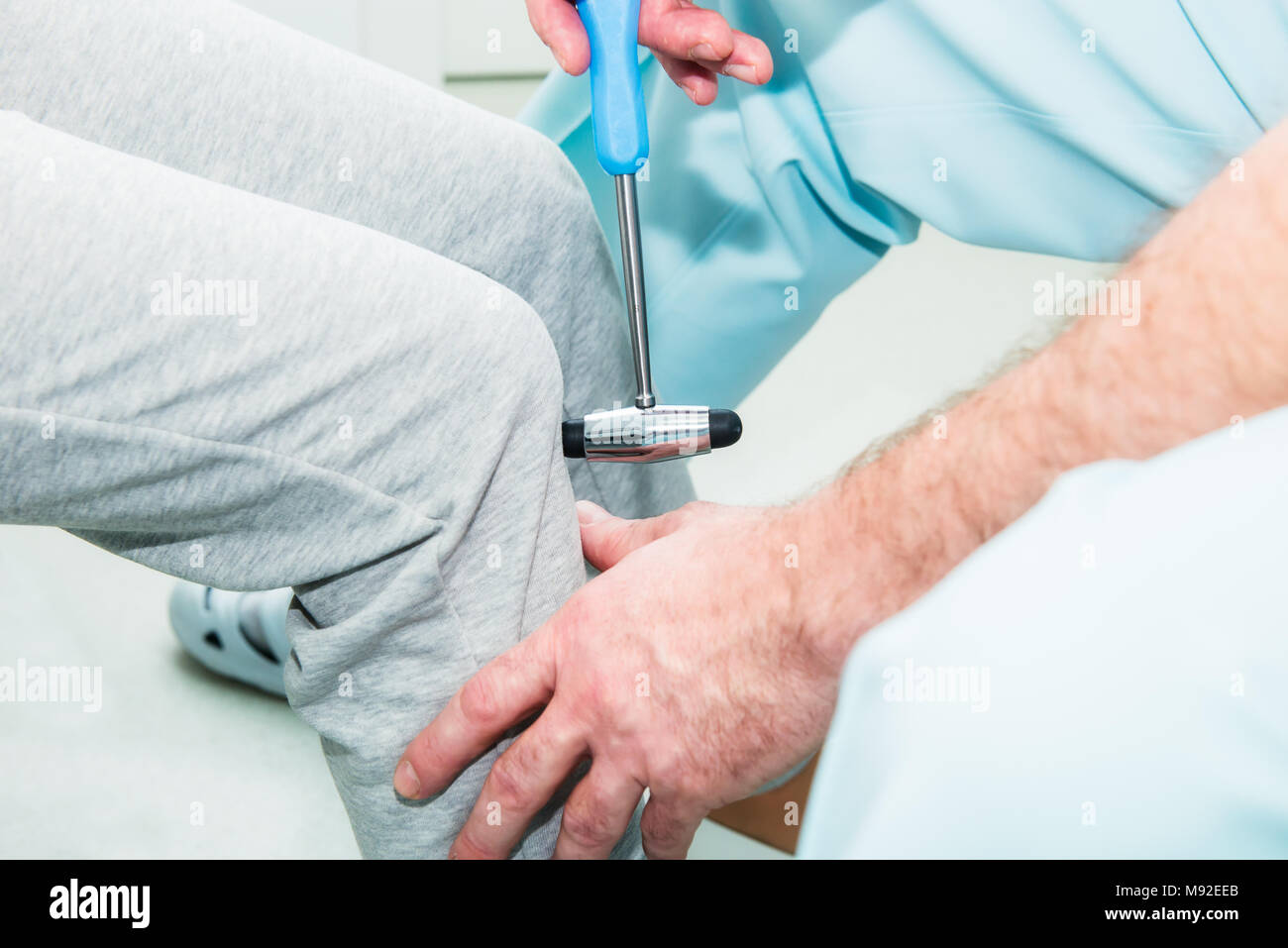 The neurologist testing knee reflex on a female patient using a hammer. Neurological physical examination. Selective focus, close up. Stock Photo