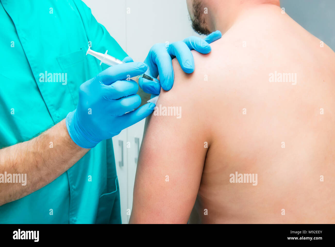 Close up Neurologist doctor makes an injection therapy (blockade) into deltoid muscle of male patient. Alternative pain treatment concept. Selective focus, space for text. Stock Photo