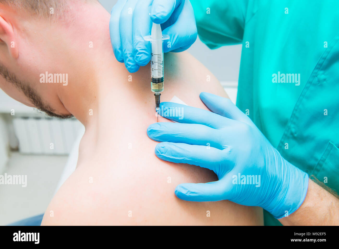 Close up Neurologist doctor makes an injection therapy (blockade) into trapezium muscle of male patient. Alternative pain treatment concept. Selective focus, space for text. Stock Photo