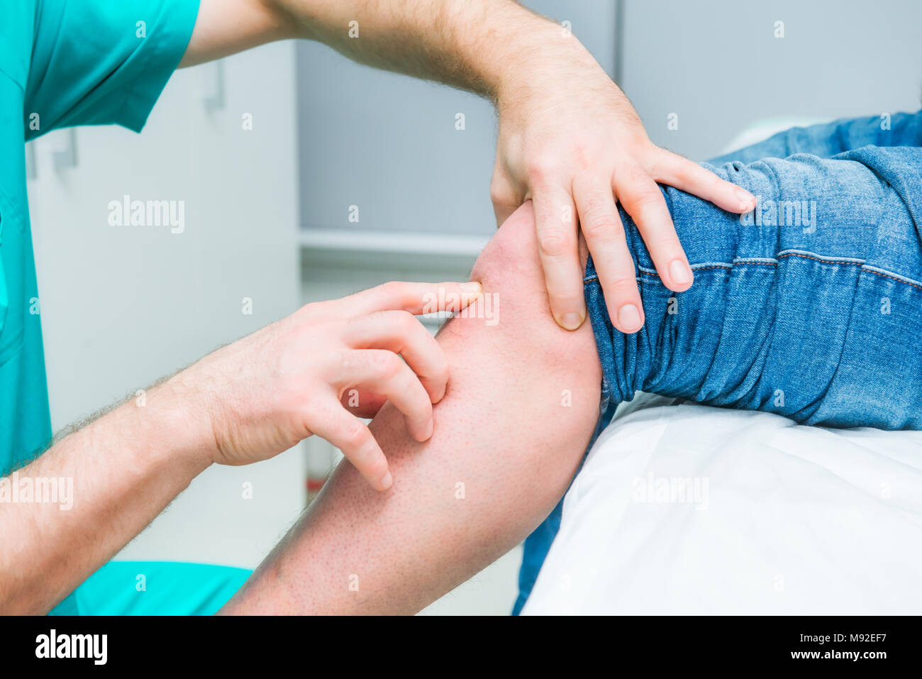 The neurologist doctor testing knee of male patient by finger pulpation. Neurological physical examination. Selective focus, close up. Space for text. Stock Photo