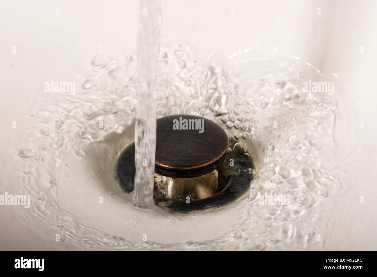 Water going down the drain in a sink basin Stock Photo