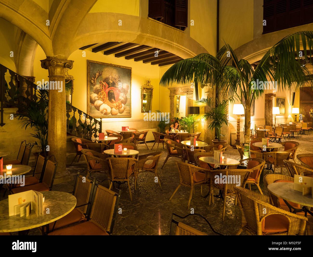 Traditional Spanish bar restaurant courtyard in Palma de Mallorca with a lone lady sitting at a table. Stock Photo