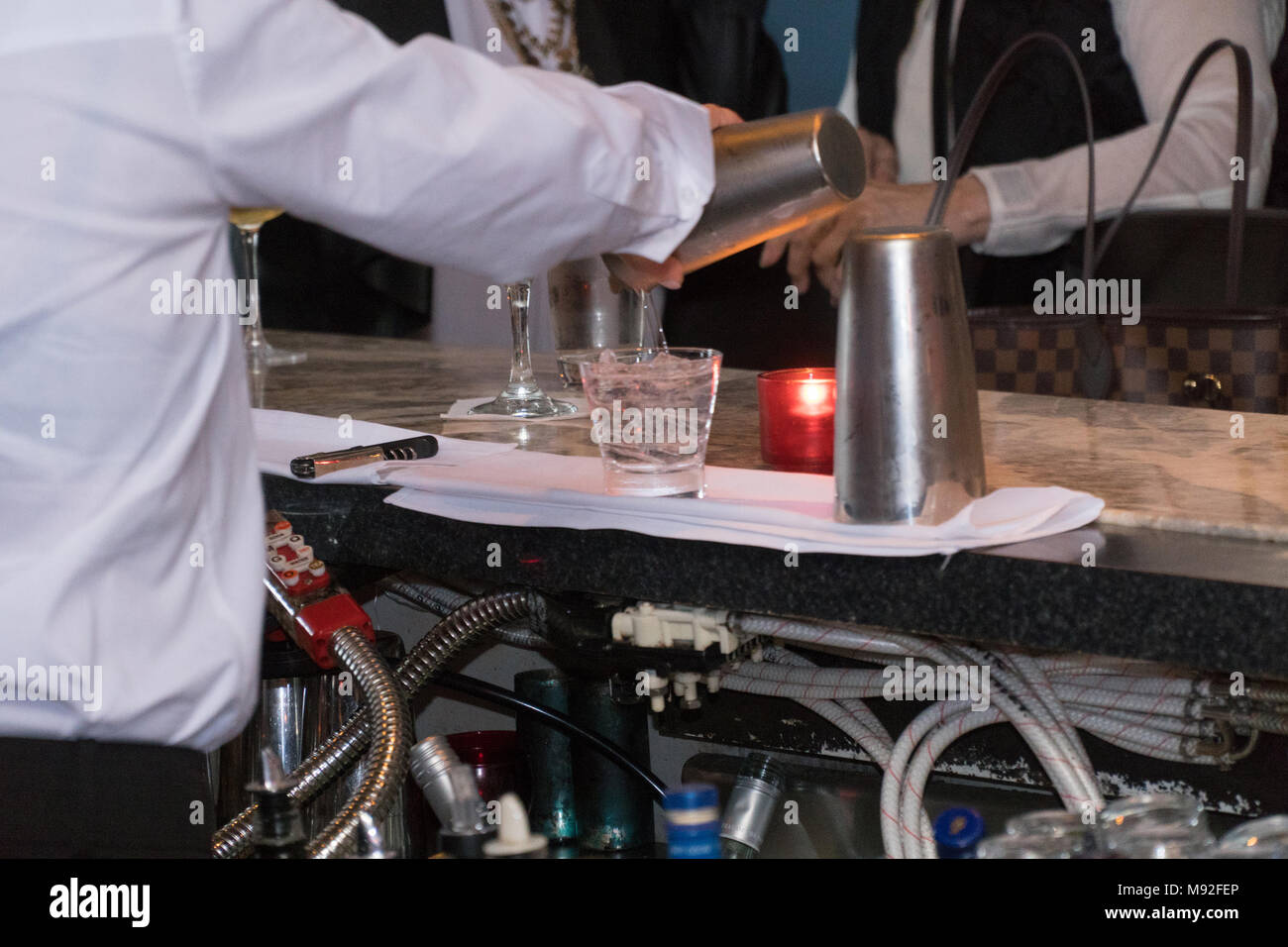 Bartender pouring mixed alcohol drink cocktails from shaker into ice