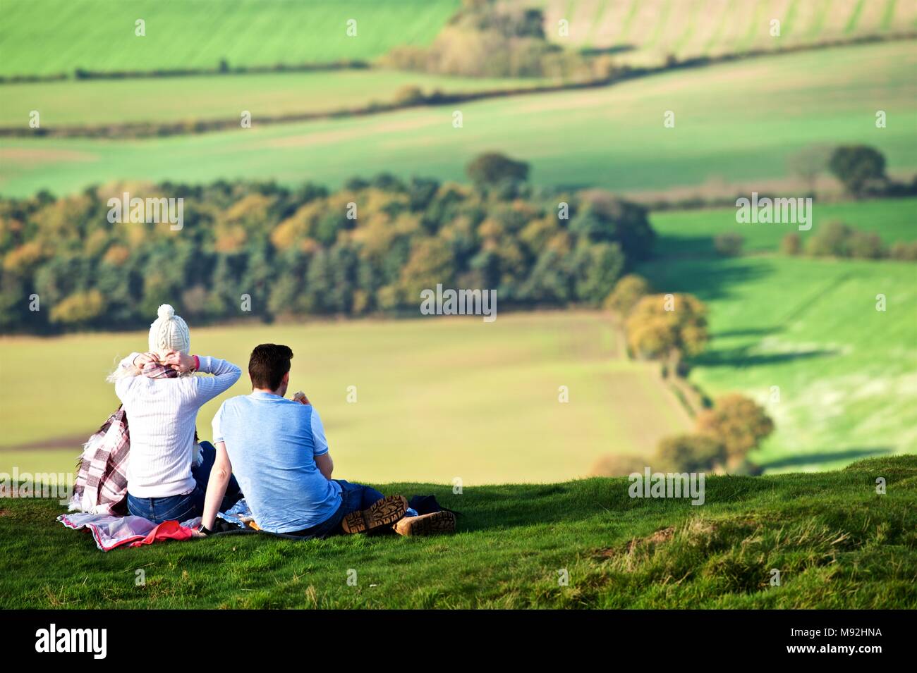 On a bright and dry Sunday afternoon in Autumn, the Wrekin attracts plenty of walkers. A young couple picnic and enjoy views over the Severn Valley Stock Photo