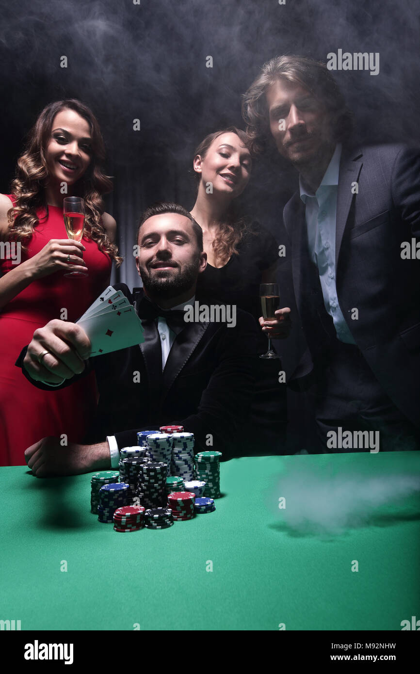 portrait of group of people with drinks playing poker in casino Stock Photo