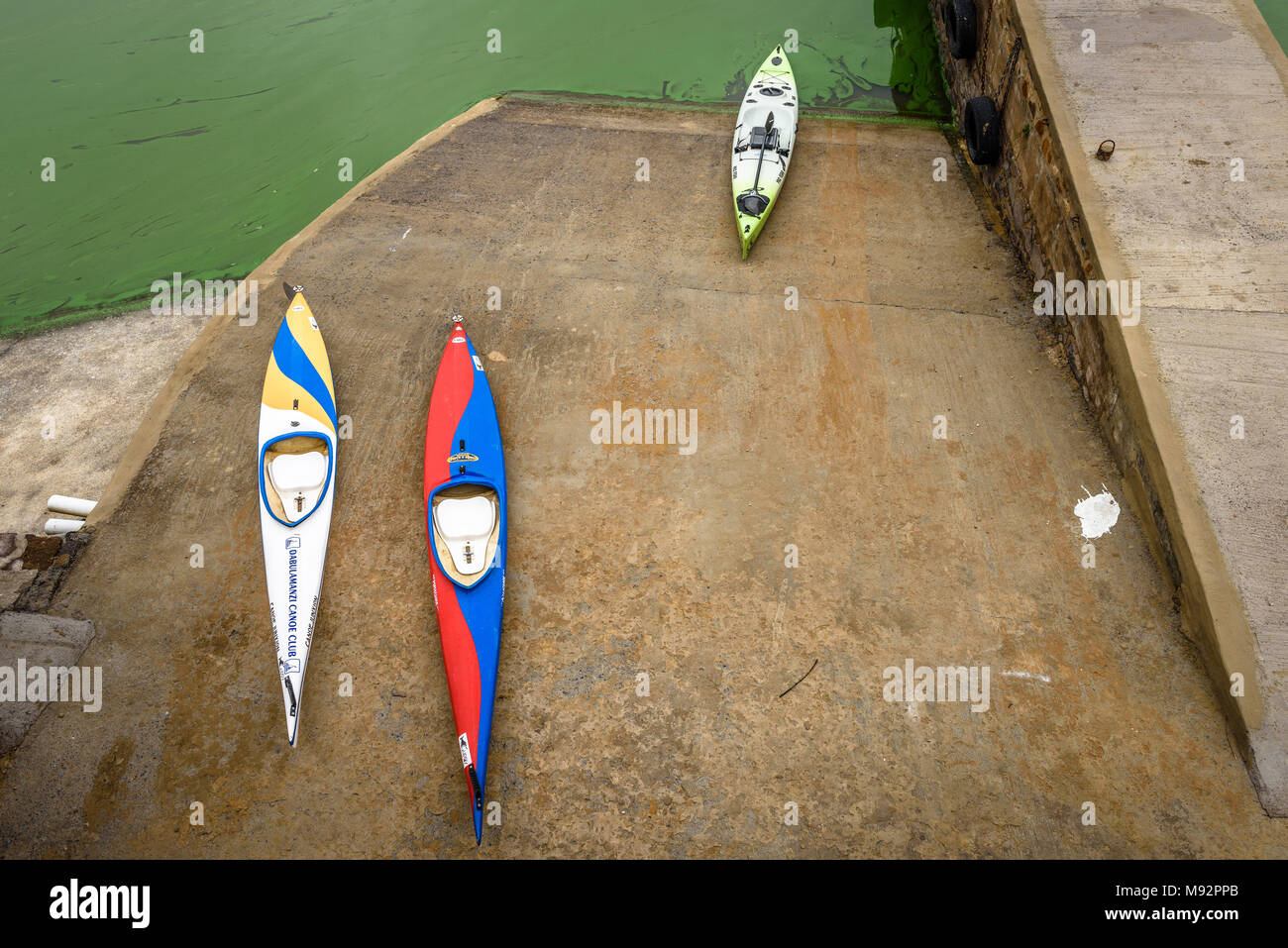 Canoes on the slipway at South Africa's Vaal dam. The algae bloom is caused by, among other factors, fertilizer runoff, also known as eutrophication Stock Photo