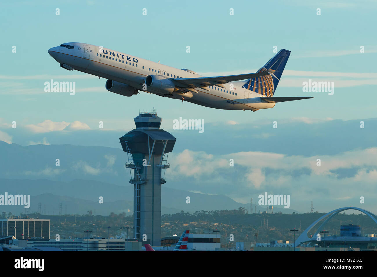 United Airlines Boeing 737-900 Jet Airliner Taking Off From Los Angeles International Airport, LAX. The Control Tower And San Gabriel Mountains Behind Stock Photo