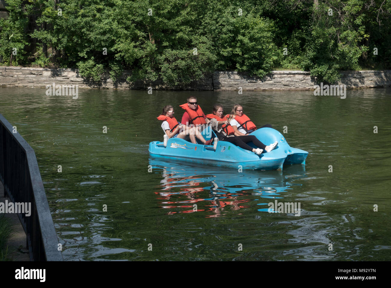 Teens entering Lake of the isles after passing thru the Lake Calhoun channel in a peddle boat wearing life vests. Minneapolis Minnesota MN USA Stock Photo