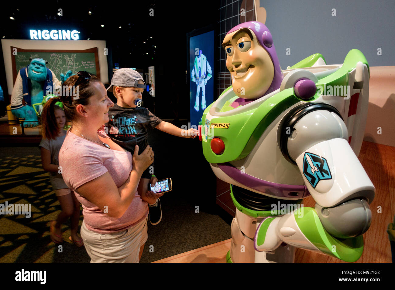 Toddler communicates with Buzz Lightyear thru a button on his chest Science Museum of Minnesota 'The Science Behind Pixar'. St Paul Minnesota MN USA Stock Photo