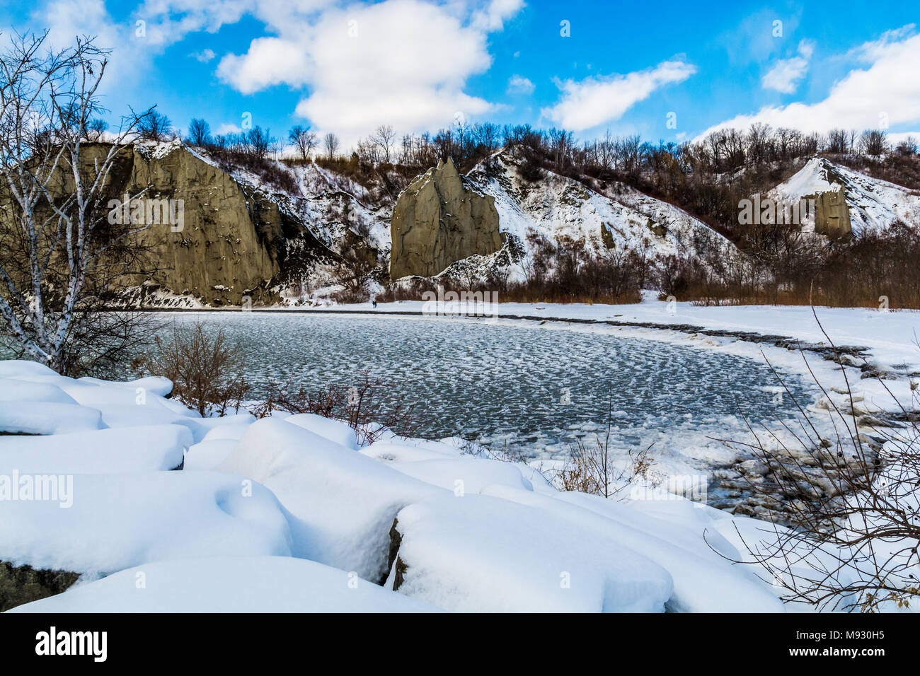 Lake Ontario in winter season showing green icy water and rocky terrain featuring rocks covered in white snow over a sunny day Stock Photo