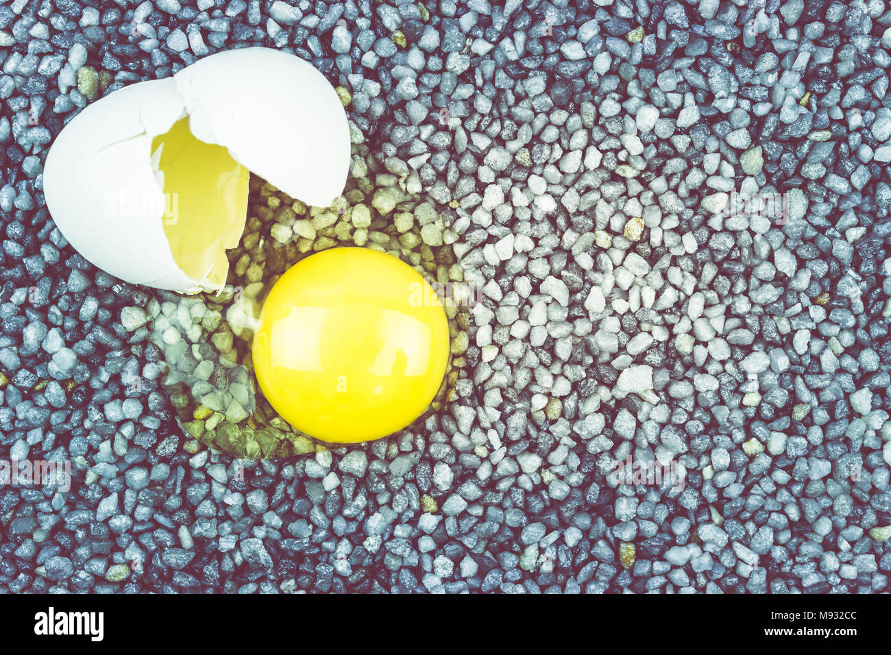 Broken egg on gray gravel, asphalt. The risk of loss, ruin. Stock Photo