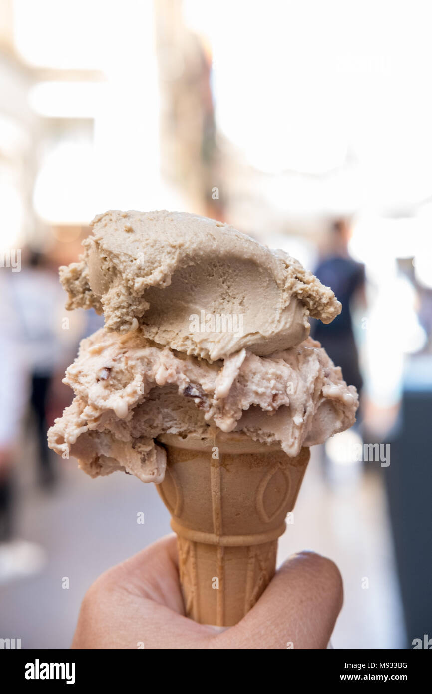 Hand holding Chocolate Gelato, Icecream with blur background of the city of Verona in Italy