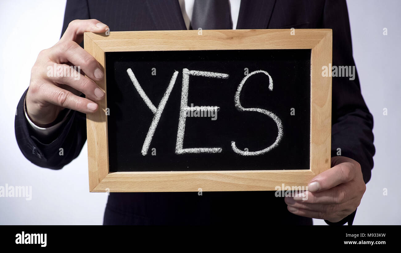 Yes written on blackboard, businessman holding sign in hands, business concept Stock Photo