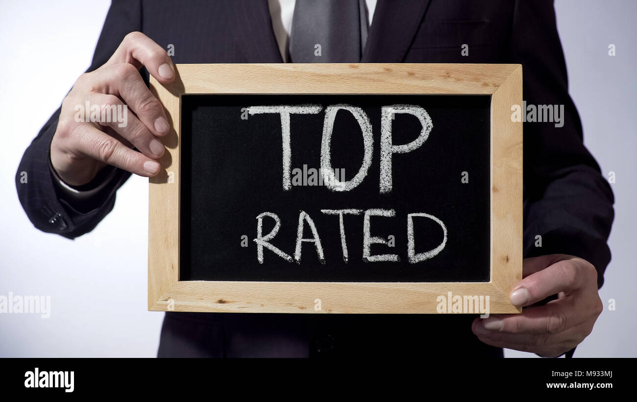 Top rated written on blackboard, business person holding sign, business concept Stock Photo