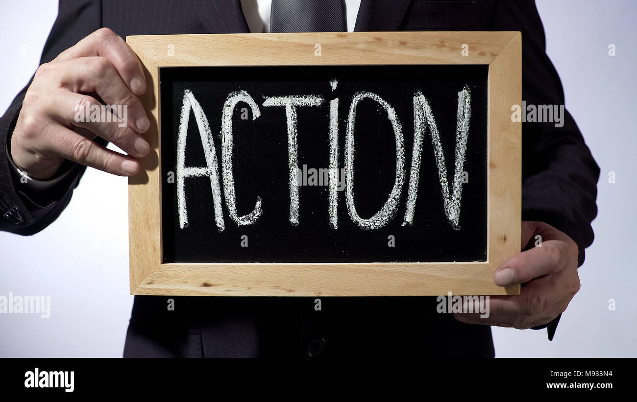 Action written on blackboard, man in black suit holding sign, business ...