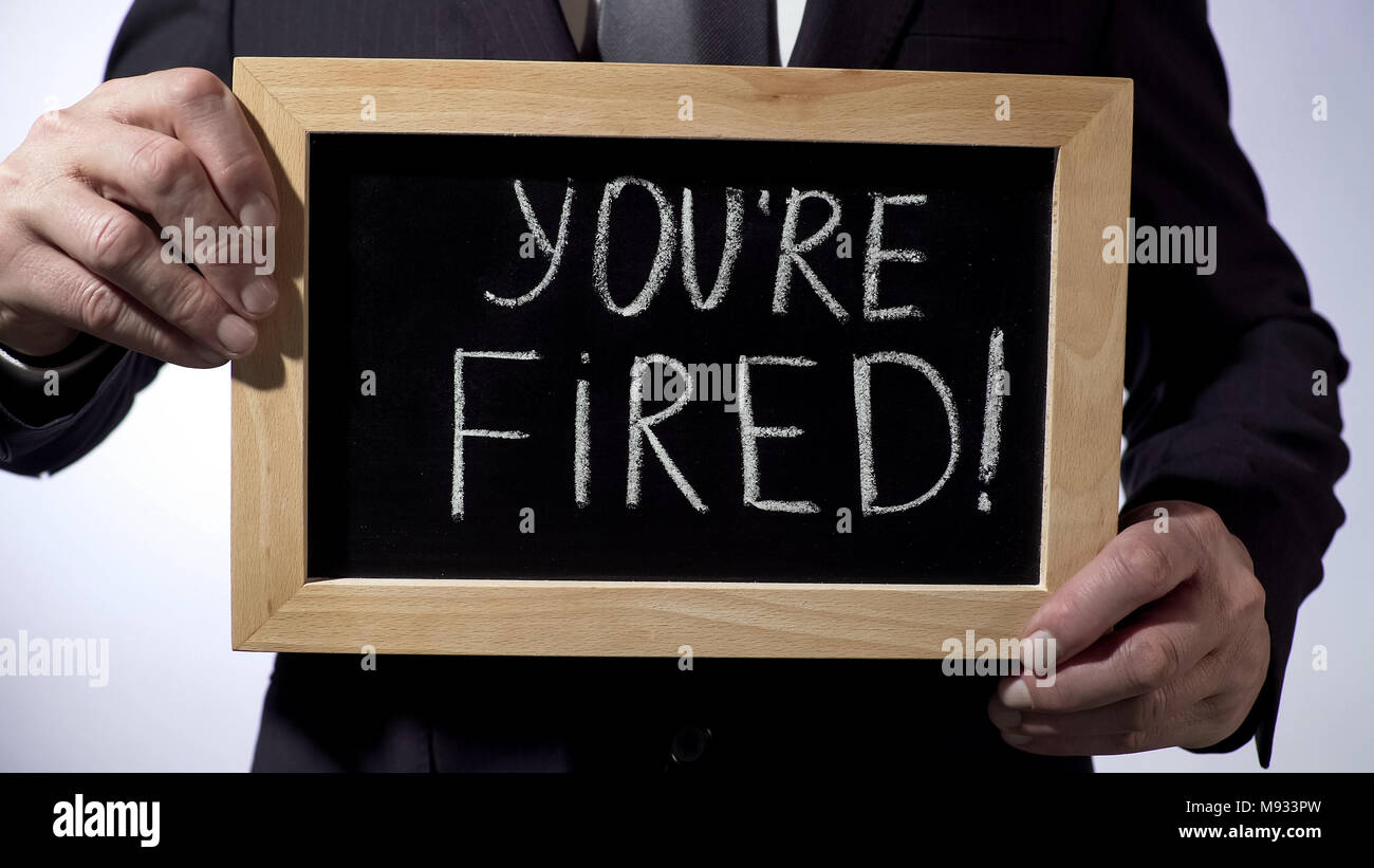 Youre fired with exclamation written on blackboard, businessman holding sign Stock Photo